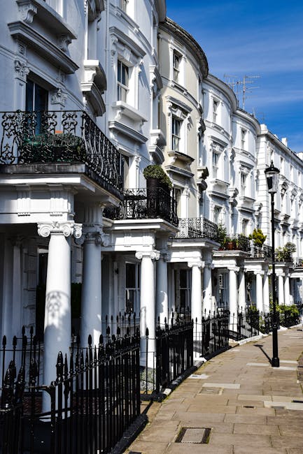 Exterior view of a row of white Victorian-style residential buildings in Belgravia, featuring elaborate architectural details like rounded bay windows, decorative cornices, and black wrought iron rail