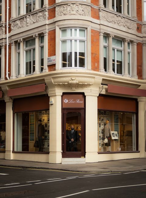 A multi-storey red brick building featuring large white-framed sash windows, decorative brickwork, and ornate detailing beneath the roofline, set against an overcast sky. In the foreground, trees with